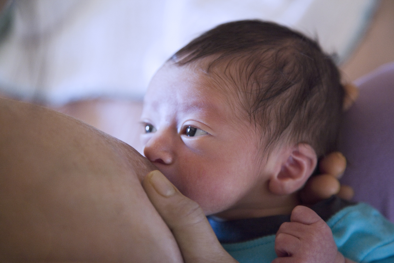 Newborn boy with large brown eyes staring at his mother as he breastfeeds enceinte preparation allaitement